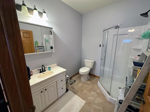 bathroom with a stall shower, baseboards, vanity, and toilet