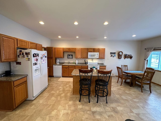 kitchen with brown cabinets, recessed lighting, a sink, white appliances, and a kitchen breakfast bar