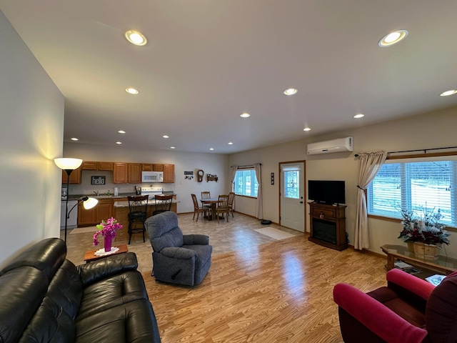 living room with a wall unit AC, light wood finished floors, a fireplace, and recessed lighting