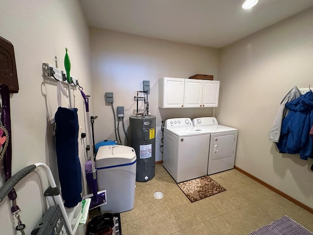 washroom featuring water heater, cabinet space, baseboards, and separate washer and dryer