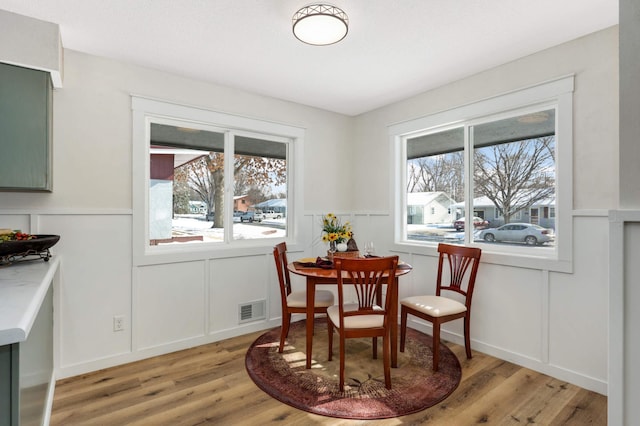 dining space with visible vents, a decorative wall, and light wood-style flooring