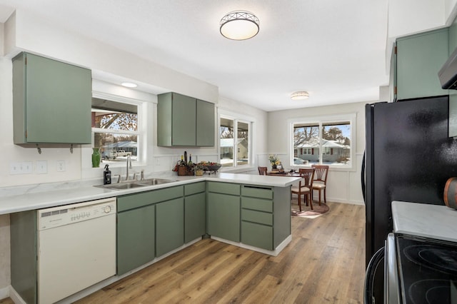 kitchen featuring black appliances, a sink, and green cabinetry