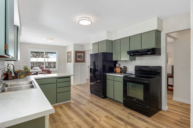 kitchen featuring green cabinetry, a sink, under cabinet range hood, and black appliances