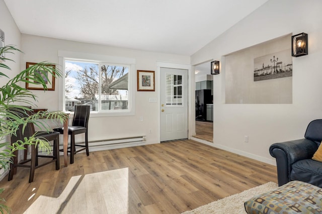 foyer entrance featuring lofted ceiling, baseboards, baseboard heating, and wood finished floors