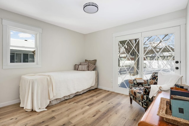 bedroom with access to outside, light wood-type flooring, and baseboards