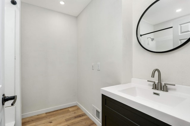 bathroom featuring visible vents, baseboards, wood finished floors, vanity, and recessed lighting