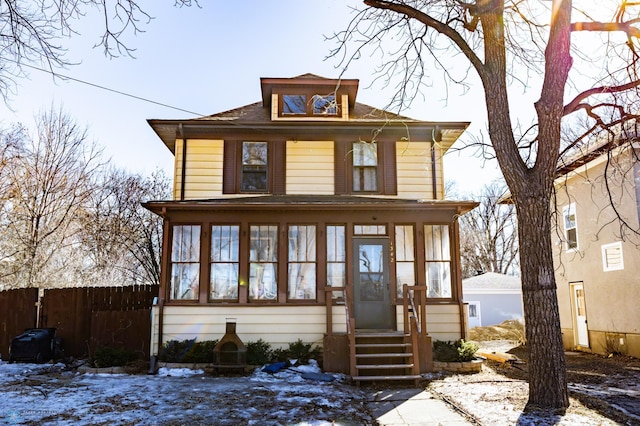 traditional style home with entry steps, a sunroom, and fence