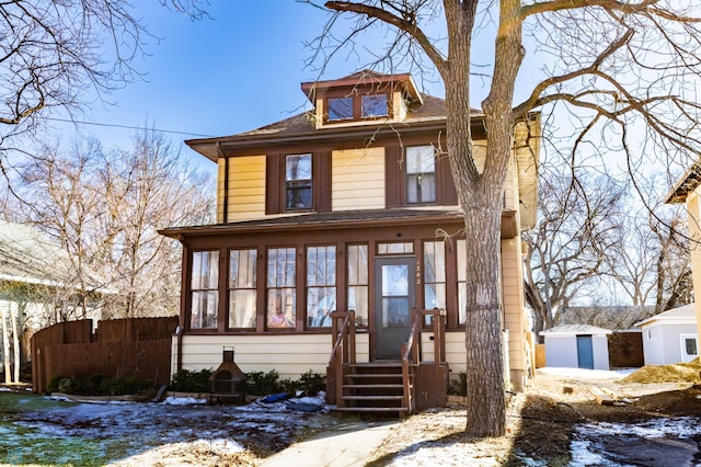 traditional style home with a sunroom, fence, and an outdoor structure