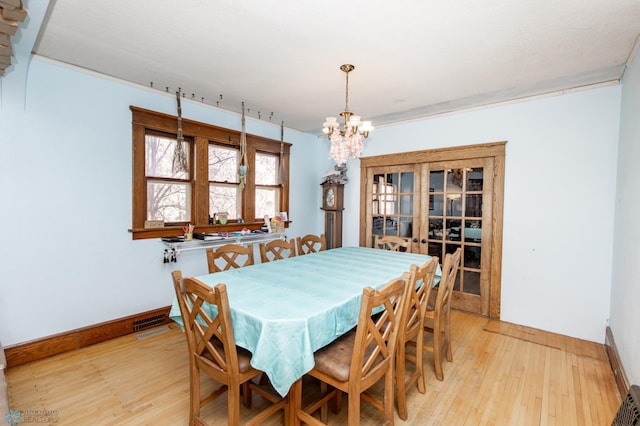 dining space featuring a chandelier, light wood-style flooring, and baseboards