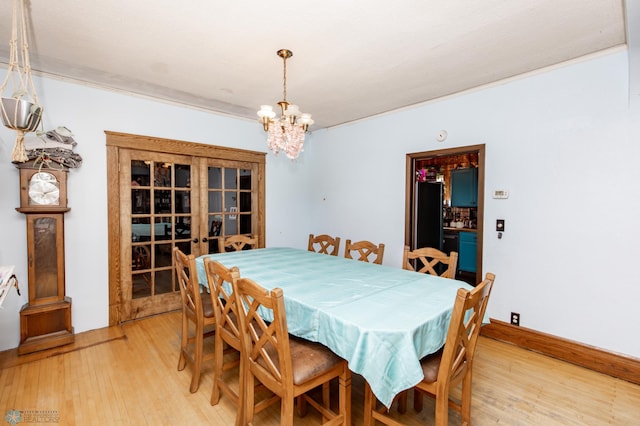 dining area featuring light wood-type flooring, a notable chandelier, and baseboards