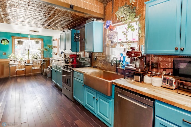 kitchen with wooden counters, appliances with stainless steel finishes, a sink, and an ornate ceiling