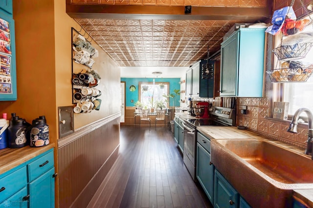 kitchen featuring an ornate ceiling, a wainscoted wall, butcher block counters, electric range, and a sink