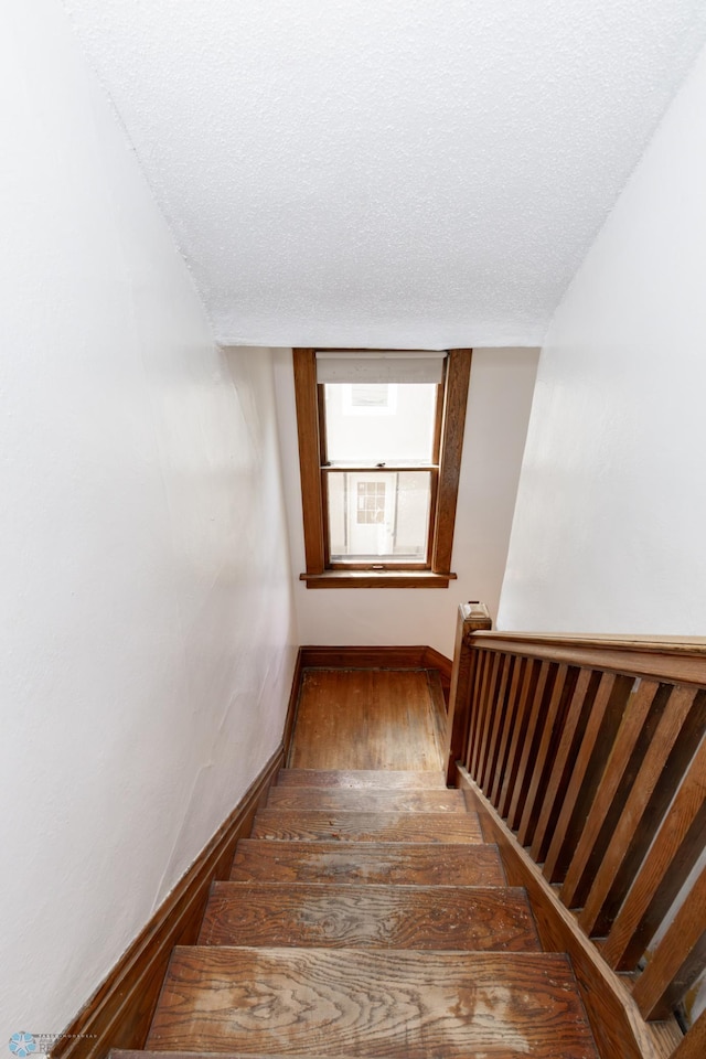 stairs featuring baseboards, a textured ceiling, and hardwood / wood-style floors