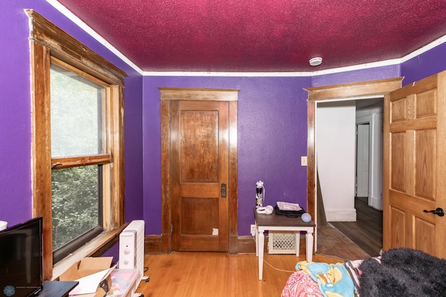 bedroom with a textured wall, a textured ceiling, and wood finished floors