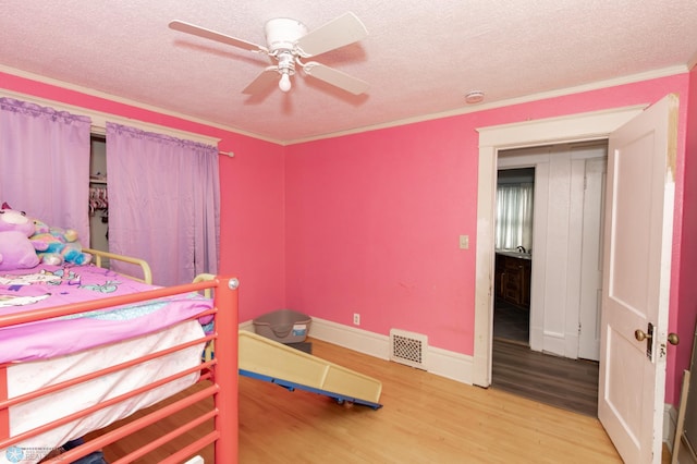 bedroom featuring a textured ceiling, visible vents, wood finished floors, and ornamental molding