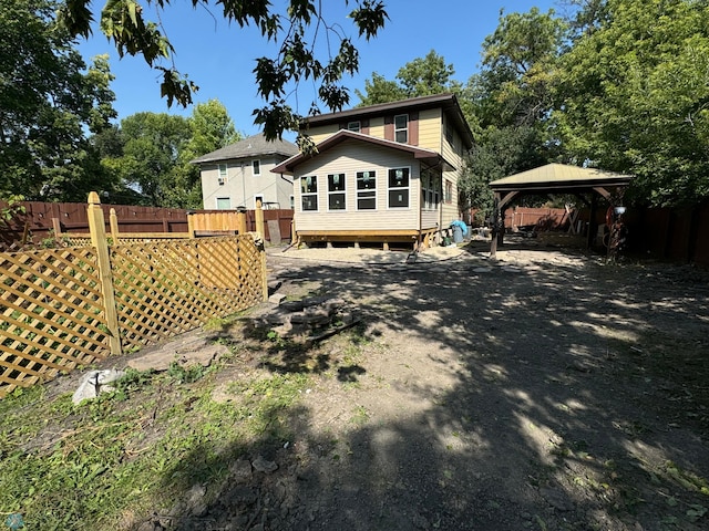 rear view of property with fence and a gazebo