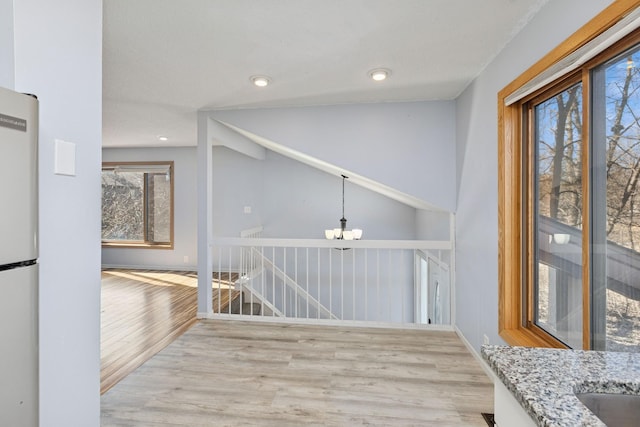 interior space with light wood finished floors, baseboards, an upstairs landing, a chandelier, and recessed lighting