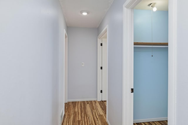 corridor with baseboards and wood finished floors