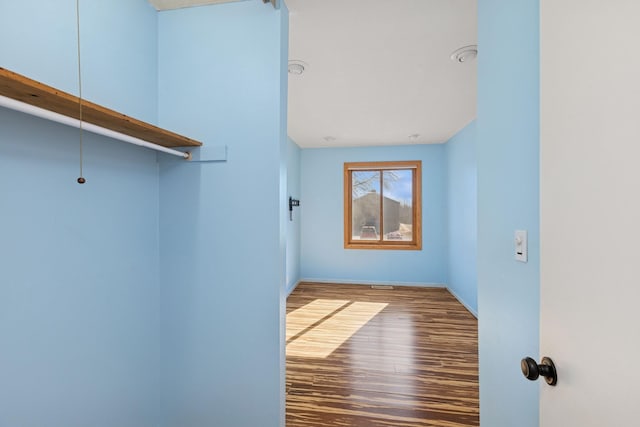 walk in closet with wood finished floors