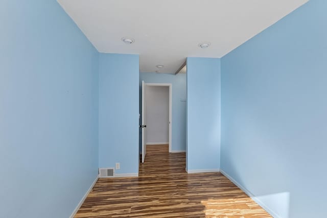 unfurnished room featuring visible vents, baseboards, and wood finished floors