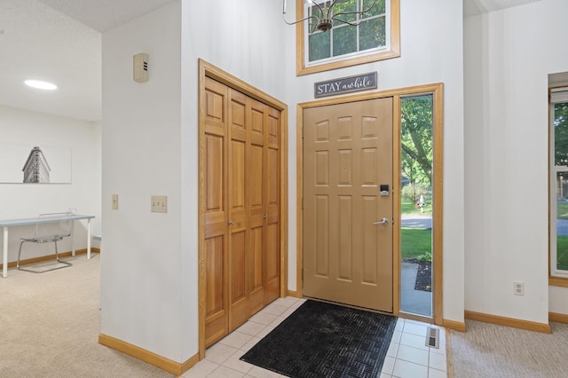 entryway featuring light carpet, light tile patterned floors, visible vents, and baseboards