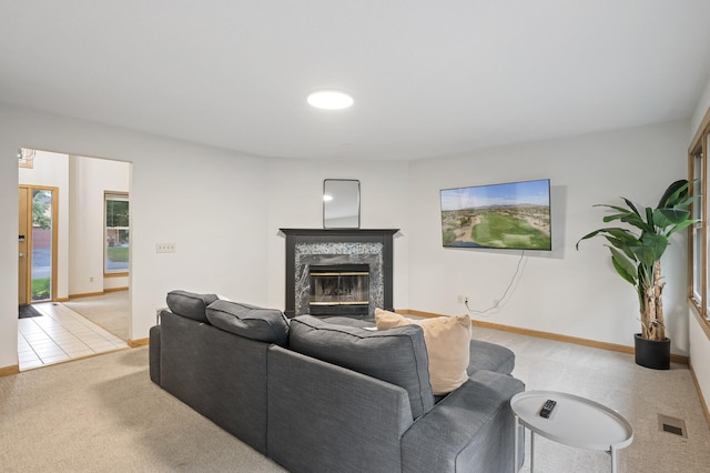 living area with light colored carpet, a fireplace, visible vents, and baseboards