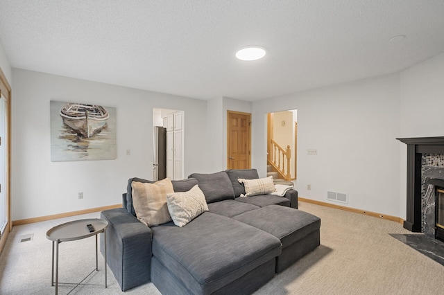 living area with light colored carpet, visible vents, stairway, a fireplace with flush hearth, and baseboards