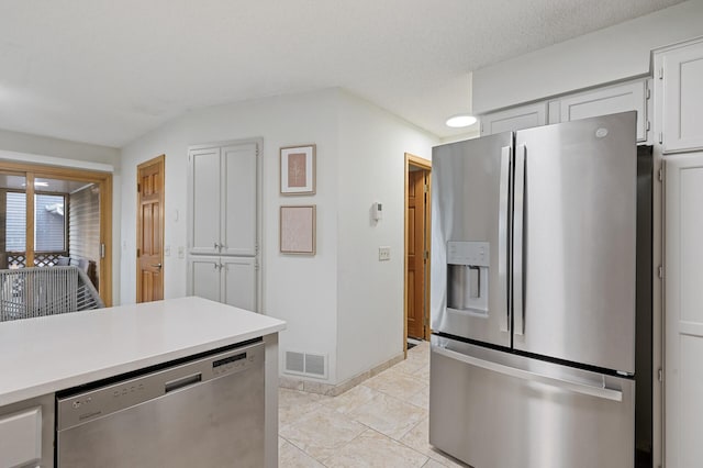 kitchen featuring a textured ceiling, stainless steel appliances, visible vents, white cabinetry, and light countertops