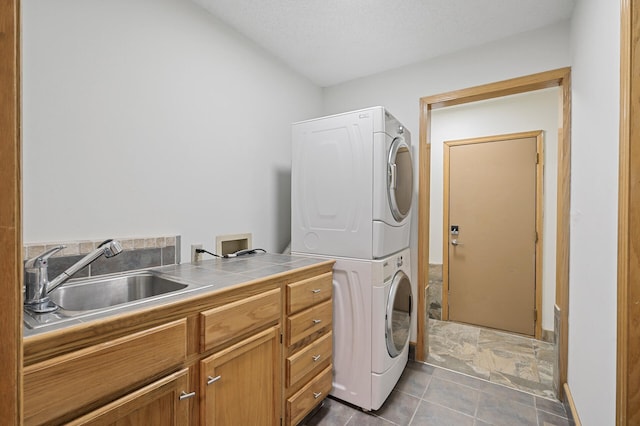 laundry room with cabinet space, a sink, and stacked washer and clothes dryer