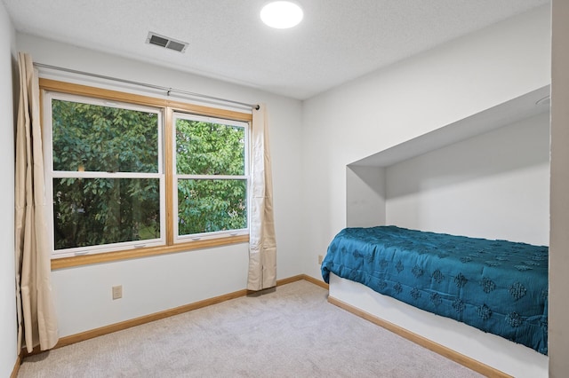 bedroom featuring carpet, visible vents, a textured ceiling, and baseboards