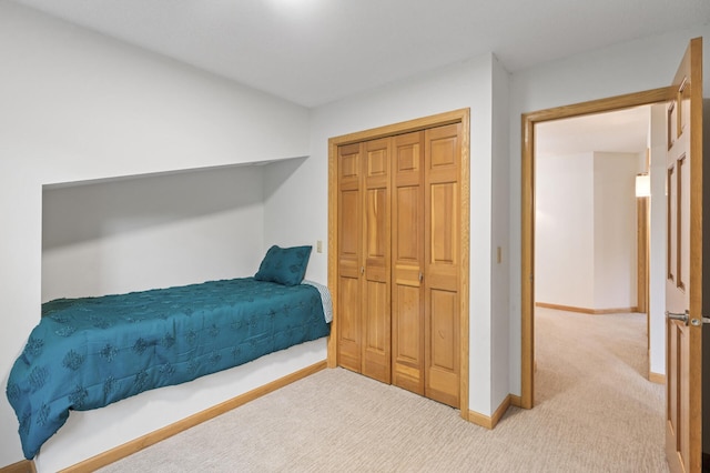 carpeted bedroom featuring a closet and baseboards