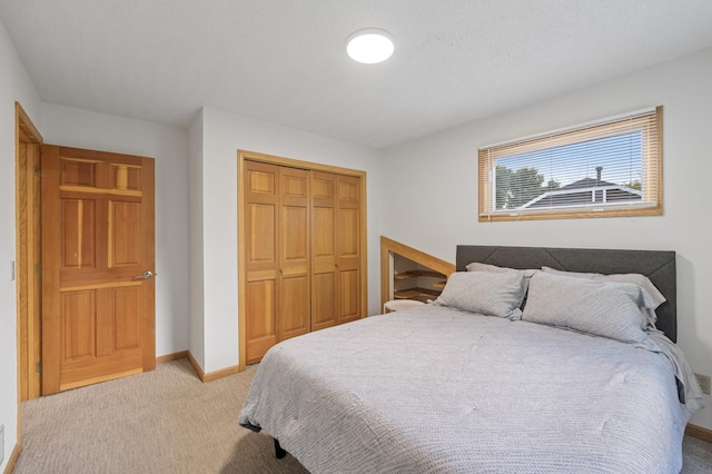 bedroom with a closet, light colored carpet, and baseboards