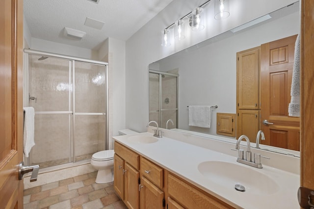 full bath featuring a textured ceiling, a stall shower, a sink, and toilet