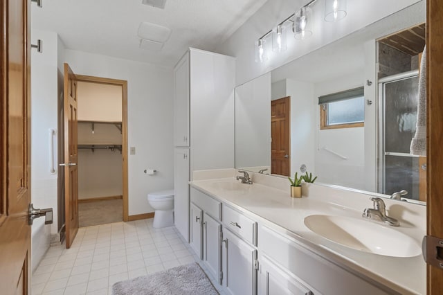 bathroom with double vanity, a stall shower, toilet, tile patterned flooring, and a sink