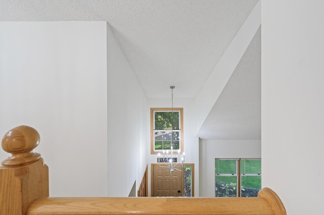 hallway featuring a textured ceiling and an upstairs landing