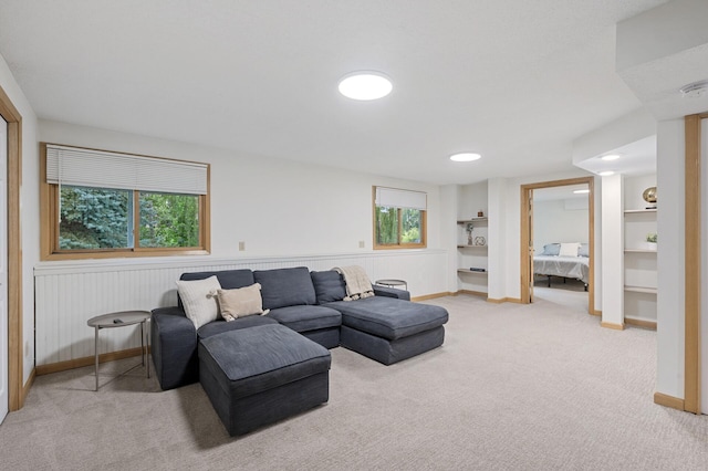 living area with a wainscoted wall, baseboards, and light colored carpet