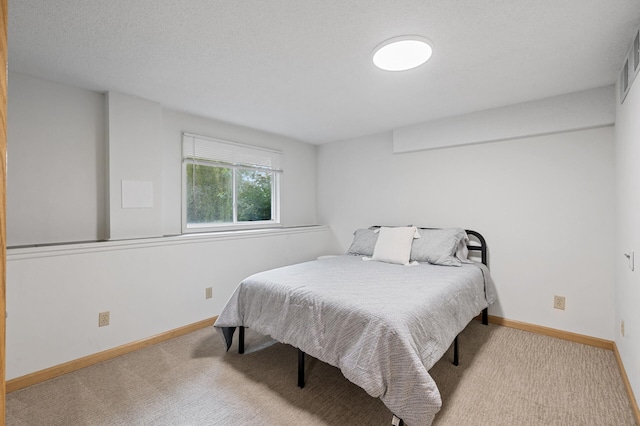 bedroom with a textured ceiling, carpet flooring, and baseboards