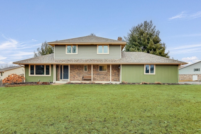 back of property with roof with shingles, brick siding, a lawn, and a chimney