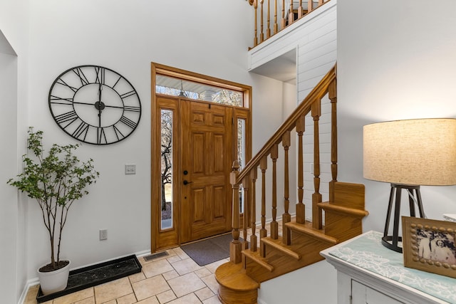 entrance foyer with stairway, baseboards, and a towering ceiling