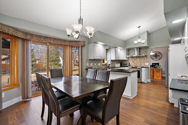 3220 Highlands Rd, Brooklyn Park, MN 55443 - dining room with a chandelier, wood finished floors, and vaulted ceiling
