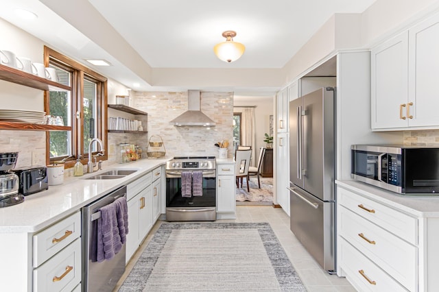 kitchen with tasteful backsplash, wall chimney exhaust hood, stainless steel appliances, open shelves, and a sink