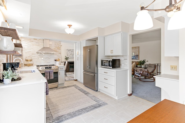 kitchen featuring appliances with stainless steel finishes, a sink, wall chimney range hood, and tasteful backsplash