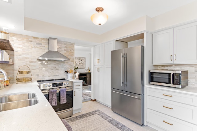 kitchen with a sink, wall chimney exhaust hood, appliances with stainless steel finishes, and backsplash