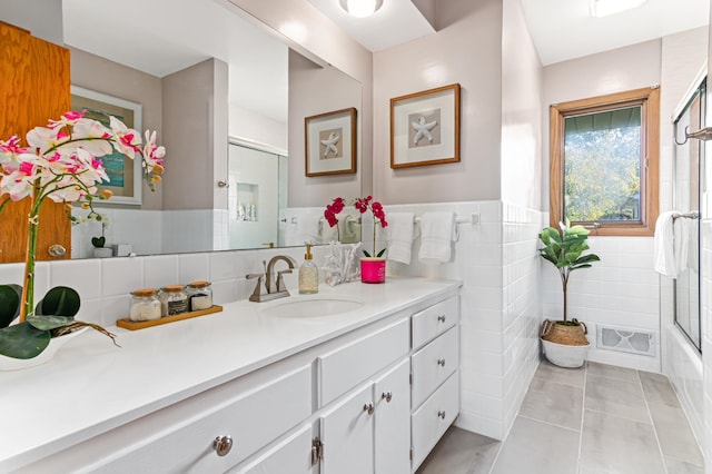 full bathroom featuring tile walls, visible vents, wainscoting, vanity, and tile patterned floors