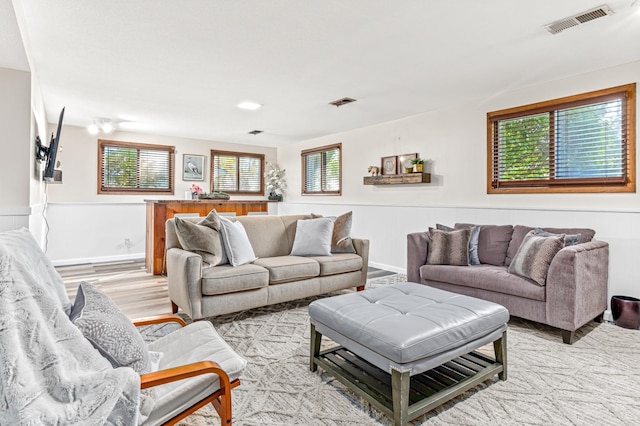 living area with light wood-style floors, visible vents, and plenty of natural light