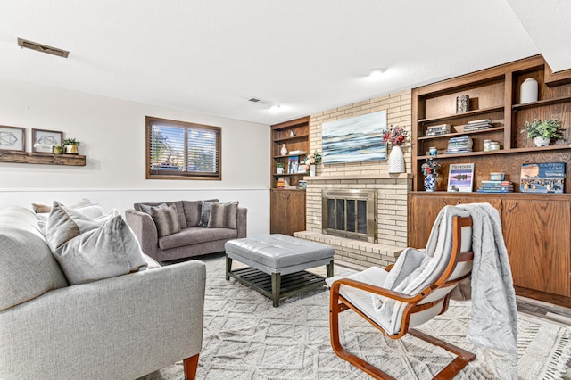 living area with built in shelves, visible vents, a fireplace, and a textured ceiling