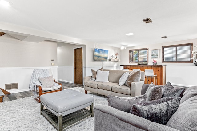 living room with wainscoting, wood finished floors, and visible vents