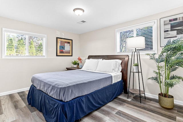 bedroom featuring visible vents, baseboards, and wood finished floors