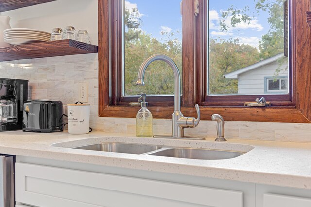 room details with light stone counters, backsplash, and a sink