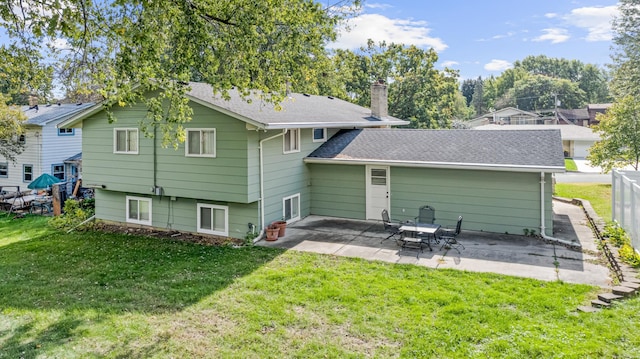 rear view of property featuring fence, a lawn, a chimney, and a patio